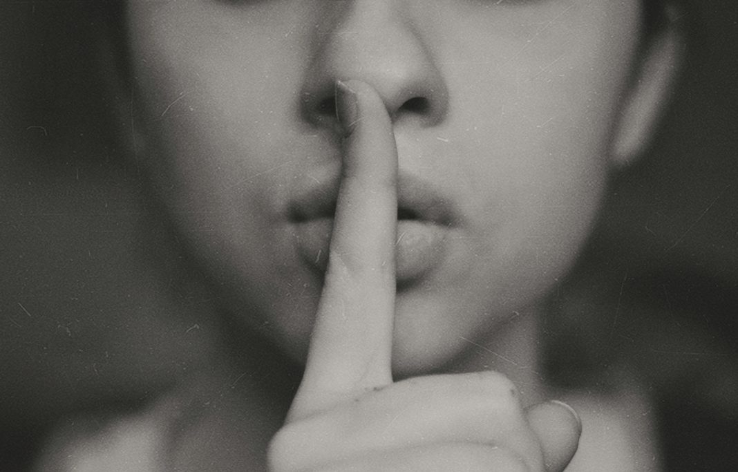 intentional silence, close up of the bottom half of someone's face with a finger held up to their mouth